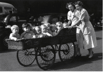 Big buggy carried by two women wit at least 10 children in it.